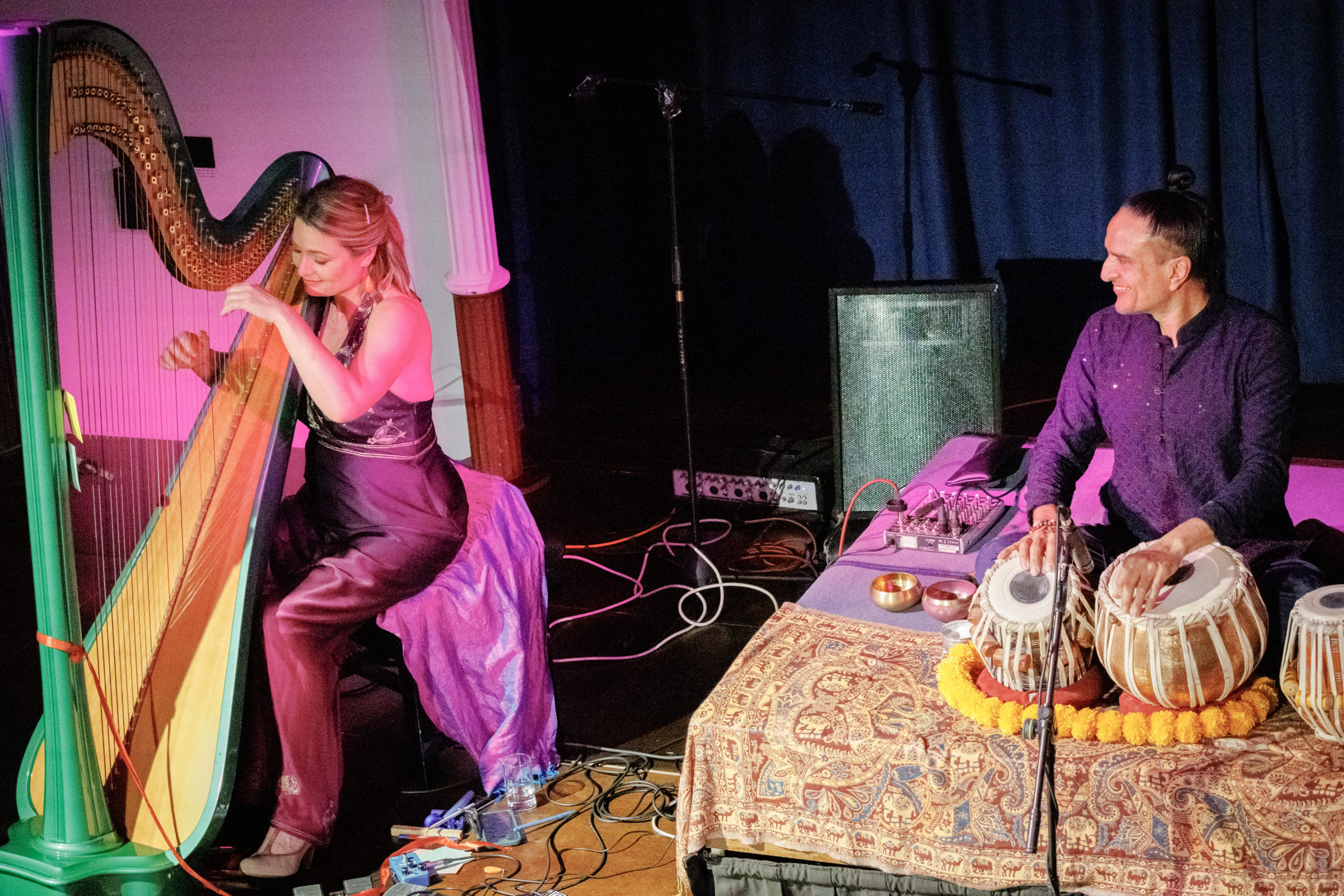 A woman plays the harp and a man plays the tabla (Indian drum)