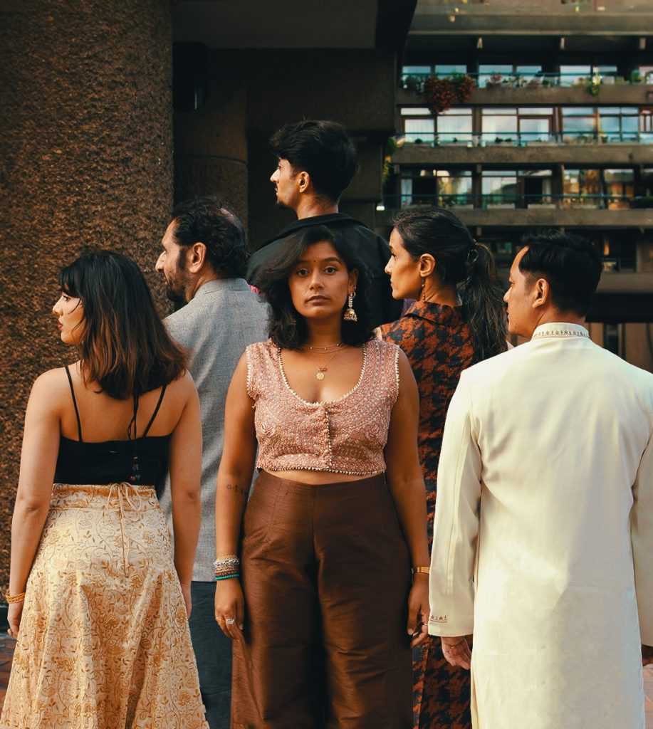 a group of 6 people with one woman facing front and everybody else has their back facing the camera