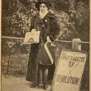 Newspaper clipping of a woman in Victorian era clothing holding a newspaper. She is standing next to a placard that reads Suffragette Revolution