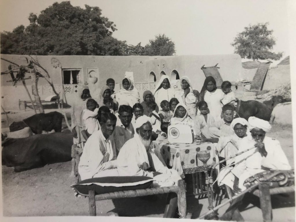 an old mono photograph of a group of people outside a building, looking towards the camera