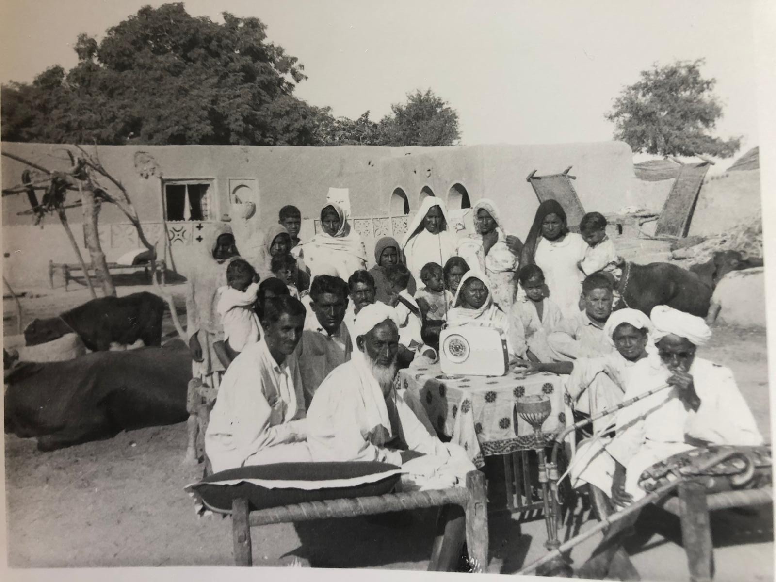 an old mono photograph of a group of people outside a building, looking towards the camera